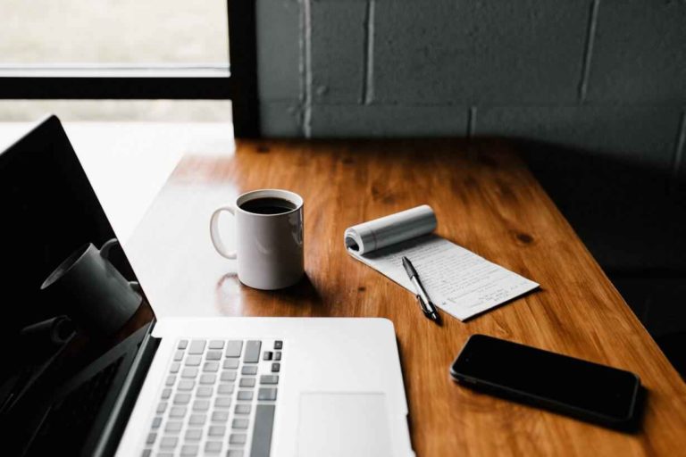 laptop on the table with a cup of coffee and notebook
