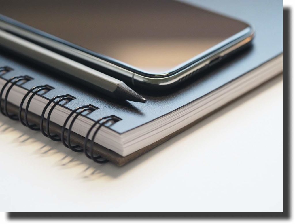 photo of black smartphone near black and grey pencil